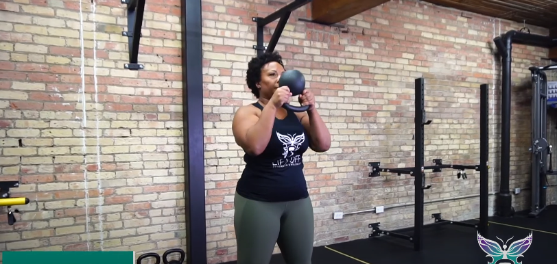 A fit person doing the kettlebell halo exercise in the gym.