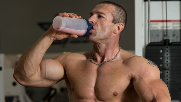 A muscular person drinking a protein shake. 