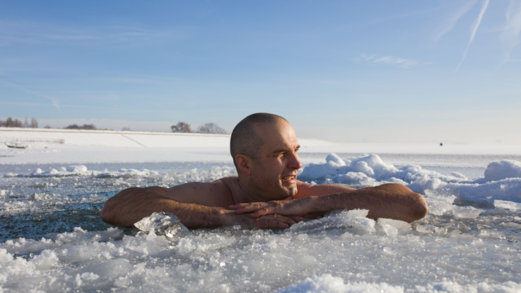 A person ice bathing in a frozen lake.