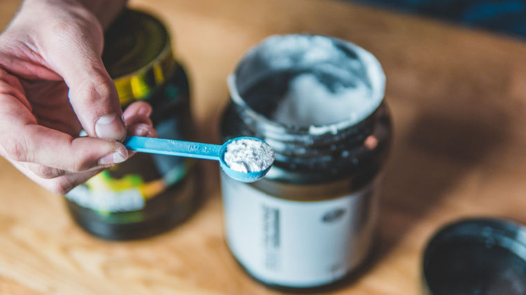 A person taking a scoop of powdered supplement.