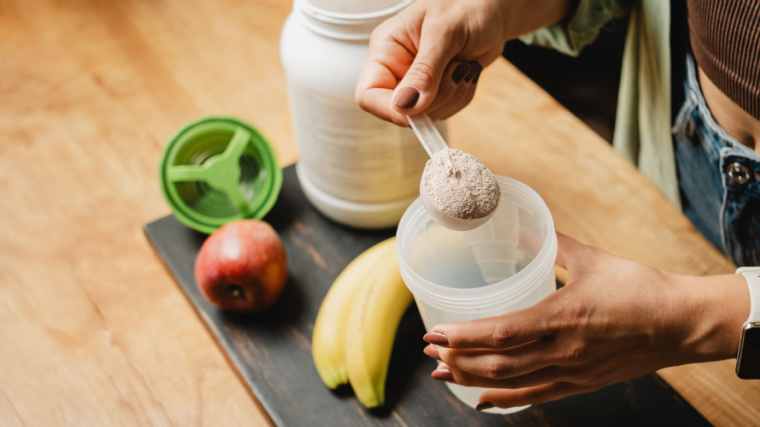 A person pouring protein powder in a shaker.