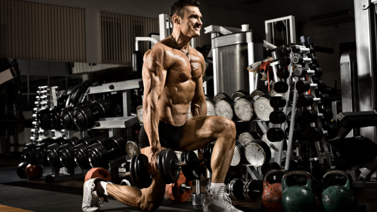 A muscular person doing the lunge exercise while carrying dumbbells.