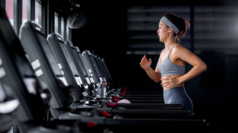 A person running on a treadmill alone in the gym. 