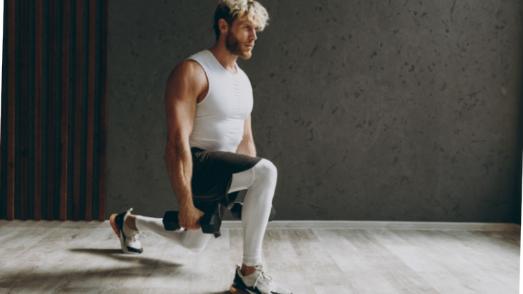 A fit person doing the walking lunge exercise while holding a dumbbells.