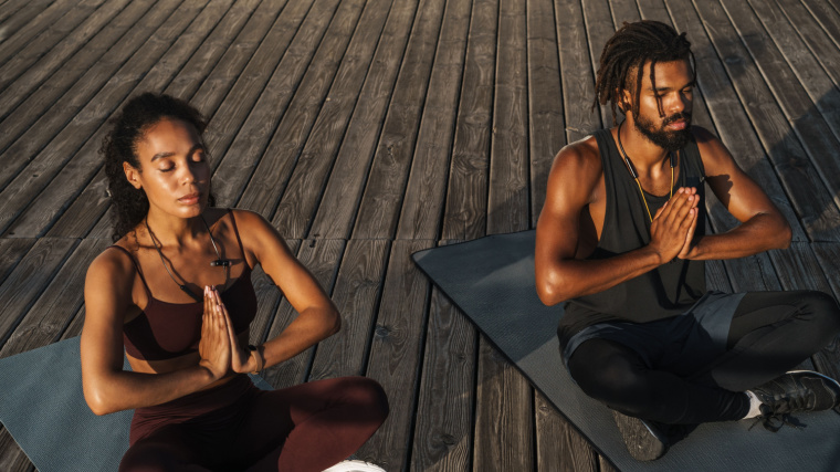A couple meditating during a yoga session outdoors.