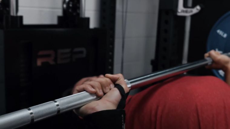 A hand holding a barbell knurling.