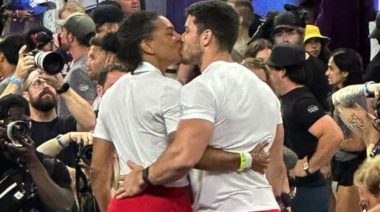 Coach Caroline Lambray and athlete Jeff Adler share a kiss wearing the classic red and white leader jerseys at the 2023 CrossFit Games.