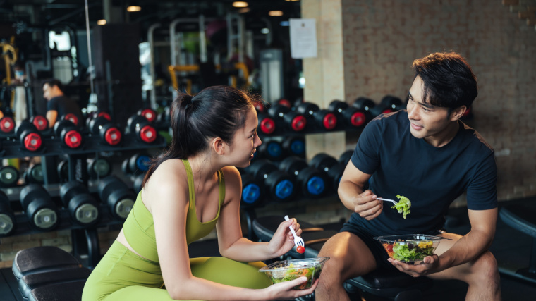 Two people eating salad after working out.