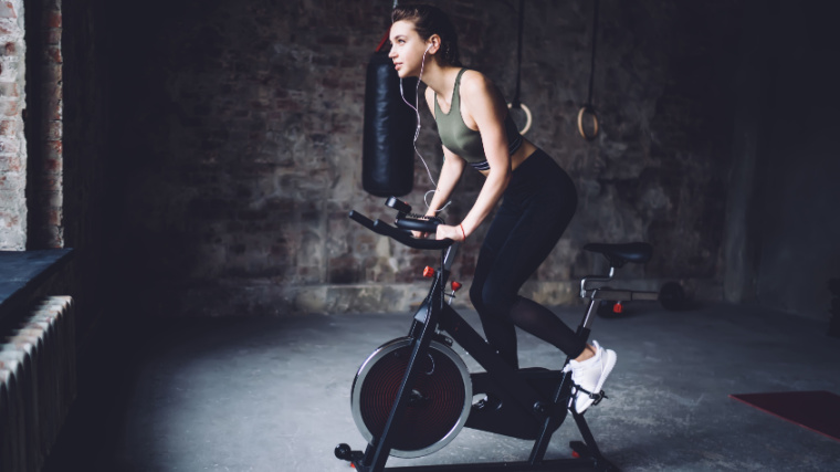 A fit person doing cardio on a stationary exercise bike.