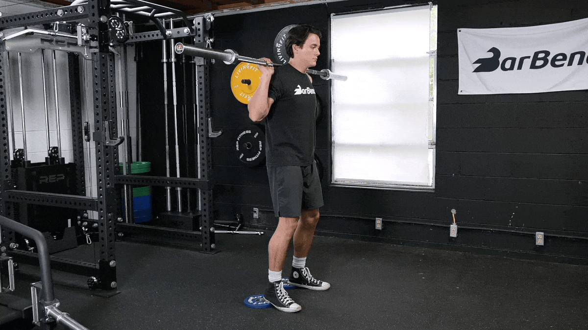 A person performing the heel-elevated back squat exercise.