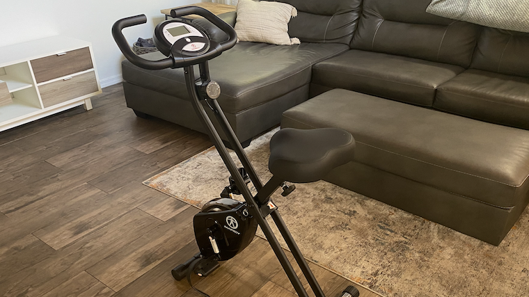 A Marcy Foldable Upright Exercise Bike is shown in a living room