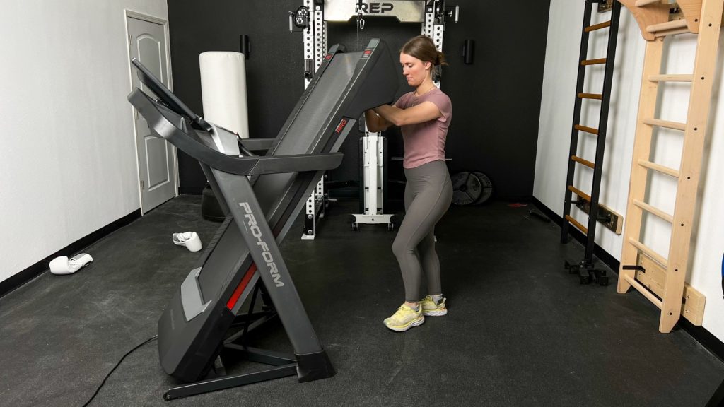 A woman folds up the ProForm Pro 9000 Treadmill.