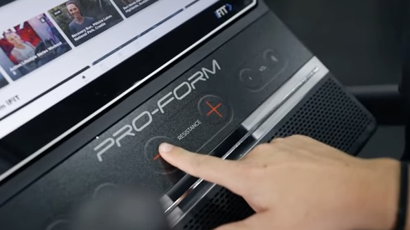 A hand reaches out to adjust the controls on a ProForm HIIT H14 stair climber.