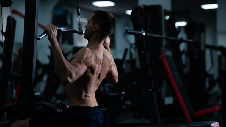 A muscular person performing the lat pulldown exercise in the gym.