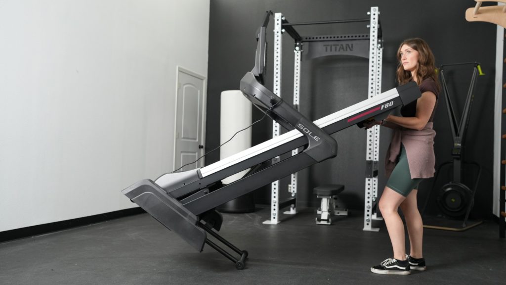 A woman moving a Sole F80 Unfolding Treadmill