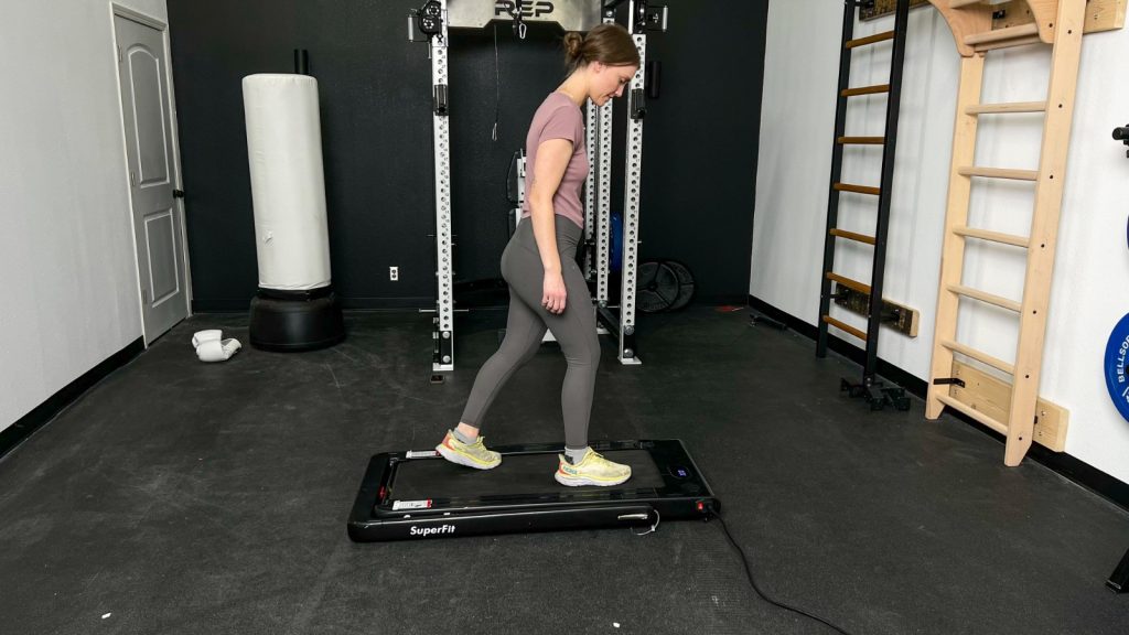 A woman walking on the Goplus 2 in 1 Folding Treadmill.