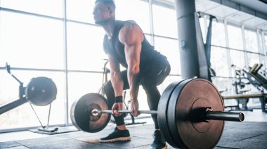 A muscular person deadlifting a barbell.