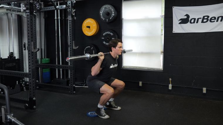 A person performing the heel elevated back squat exercise.