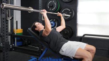 A person performing the incline barbell bench press exercise.