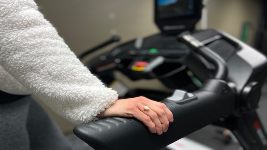 Our Tester's hand resting on the handle of a Bowflex Treadmill