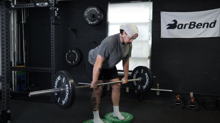 A person performing the deficit deadlift exercise.