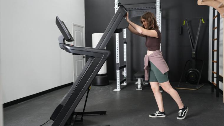 A woman is shown folding up the NordicTrack Commercial 1250 Treadmill.
