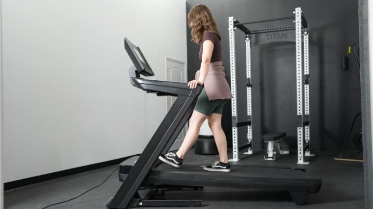 A woman stands at an incline on the NordicTrack Commercial 1250 Treadmill.