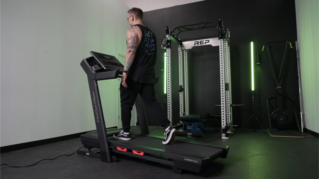 A person is shown walking on a ProForm Carbon TLX treadmill.
