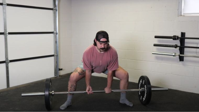 A person doing the sumo deadlift exercise.