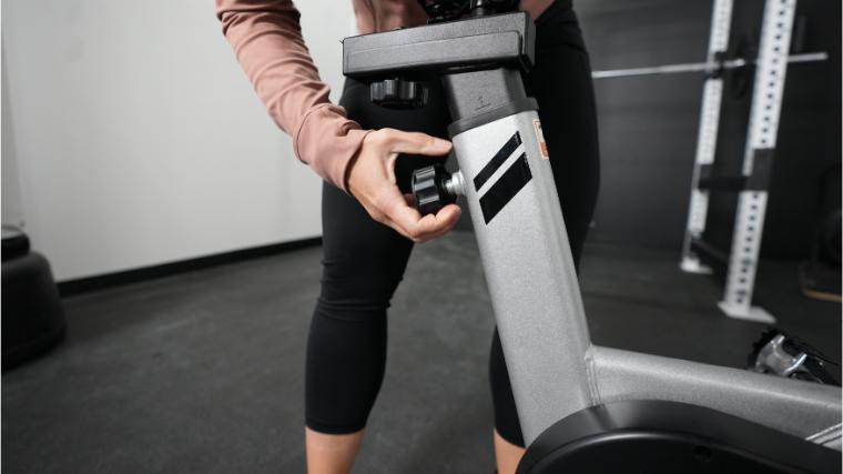 A person is shown adjusting the seat stack on the Yosuda Indoor Cycling Bike.