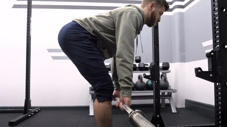 A person performing the Romanian deadlift, view from the right side.