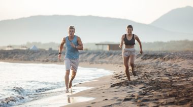Two people running on the sandy beach.