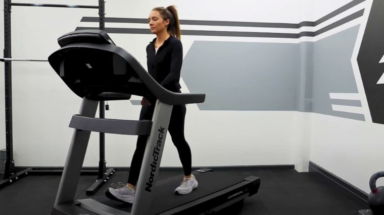 A BarBend tester walking on a treadmill in the gym.