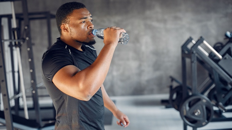 A person in the gym drinking water from a bottle.