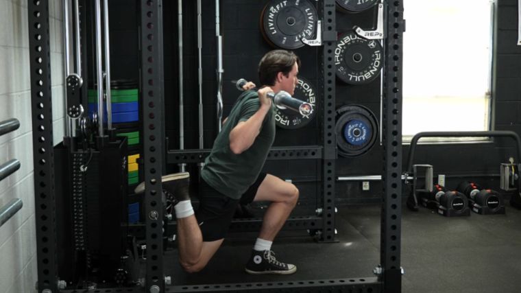 A person performing the barbell Bulgarian split squat.