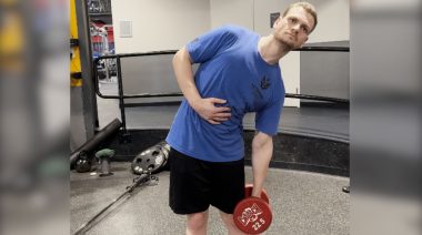 A person performing the dumbbell side bend exercise.