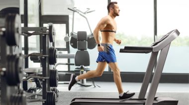 A person running on a treadmill with a chest heart rate monitor.