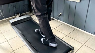 Are walking pads worth it? This image shows a person on a walking pad set partially under a desk.