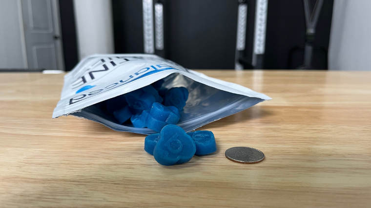 An open bag of Bear Balanced Creatine Gummies with size compared to a quarter.