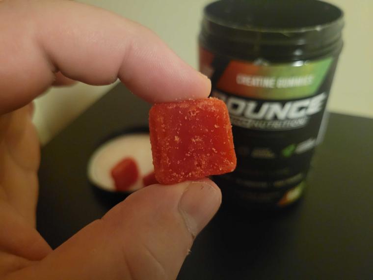 A person holding a single creatine gummy from Bounce Nutrition