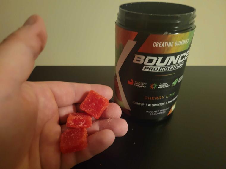 A person holds three gummies, the serving size for Bounce Creatine Gummies