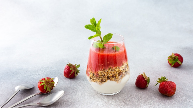 A glass with muesli and yogurt and strawberry smoothie.