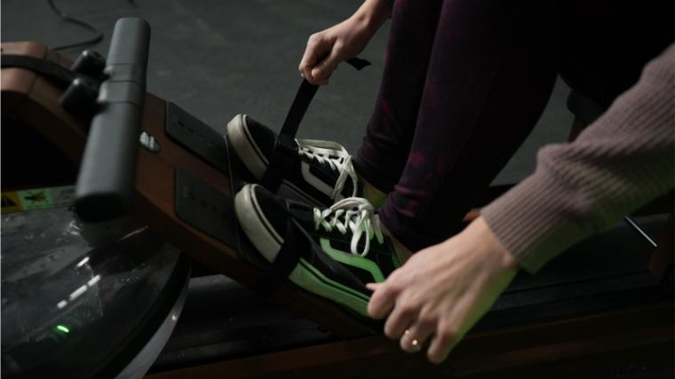 Our tester strapping in their feet on the Ergatta Rower.