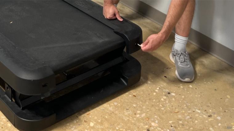 A person loosening the belt the NordicTrack X32i treadmill. 