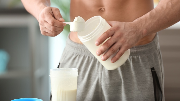 A fit person making a protein shake,
