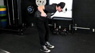 A person performing the reverse flye exercise with dumbbells.