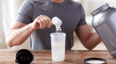 A person scooping creatine into a cup.