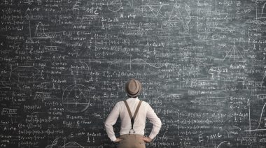 A man looking at mathematical equations on a chalkboard