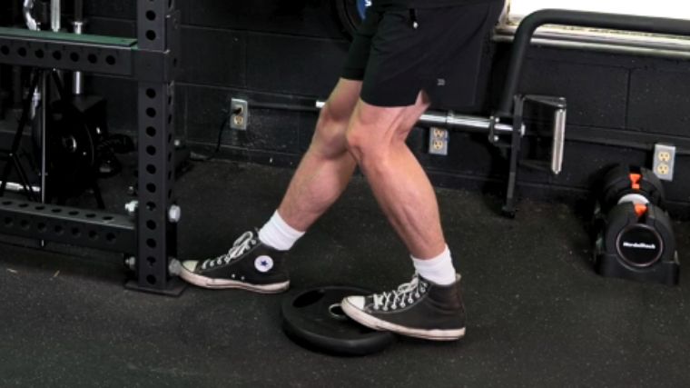 A closer view of the calves being stretched during a standing soleus stretch.