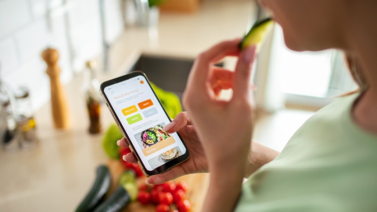 A person using a meal planning app on a smartphone to monitor weight. 